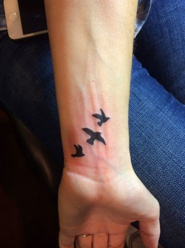 Black Ink Flying Birds Tattoo On Wrist