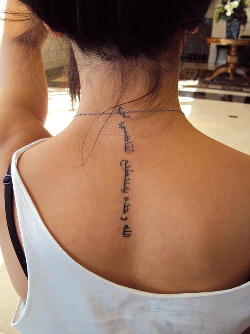 Girl Showing Her Arabic Tattoo On Upper Back