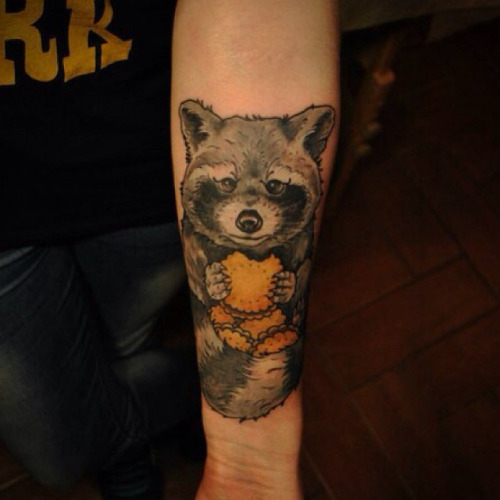 Raccoon Eating Cookies Tattoo On Forearm