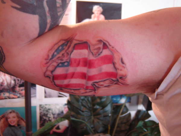 Ripped Skin American Flag Tattoo On Bicep