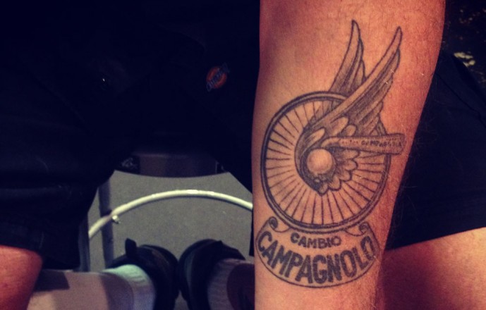 Bike Wheel With Wing And Banner Tattoo Design