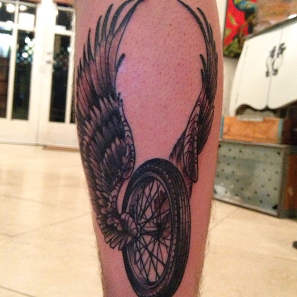 Bike Wheel With Wings Tattoo On Leg