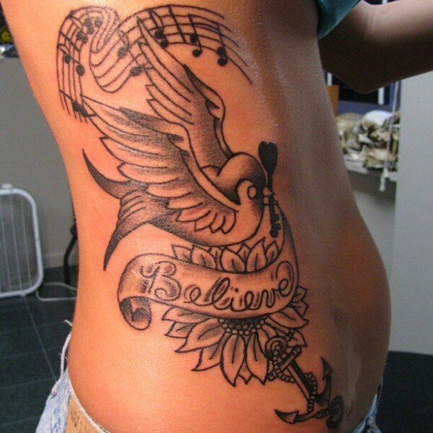 Flying Bird With Banner And Flower Tattoo On Side Belly