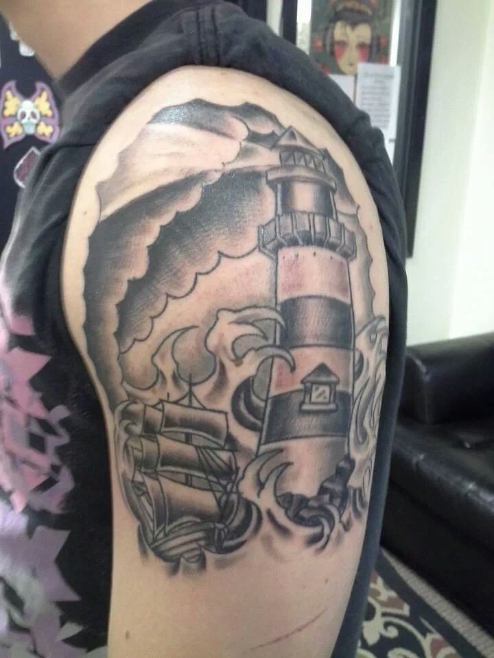Grey Ink Ship And Lighthouse Tattoo On Left Shoulder