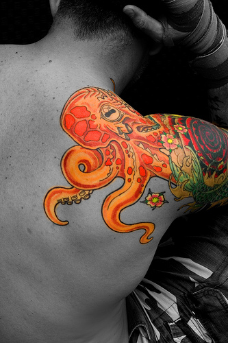 Orange Ink Octopus Tattoo On Right Shoulder