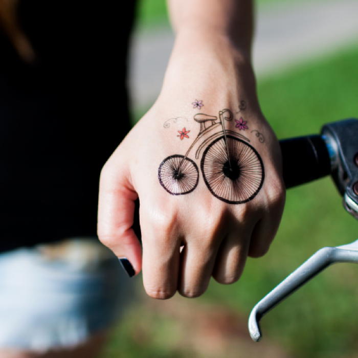 Penny Farthing Bike With Flowers Tattoo On Girl Hand