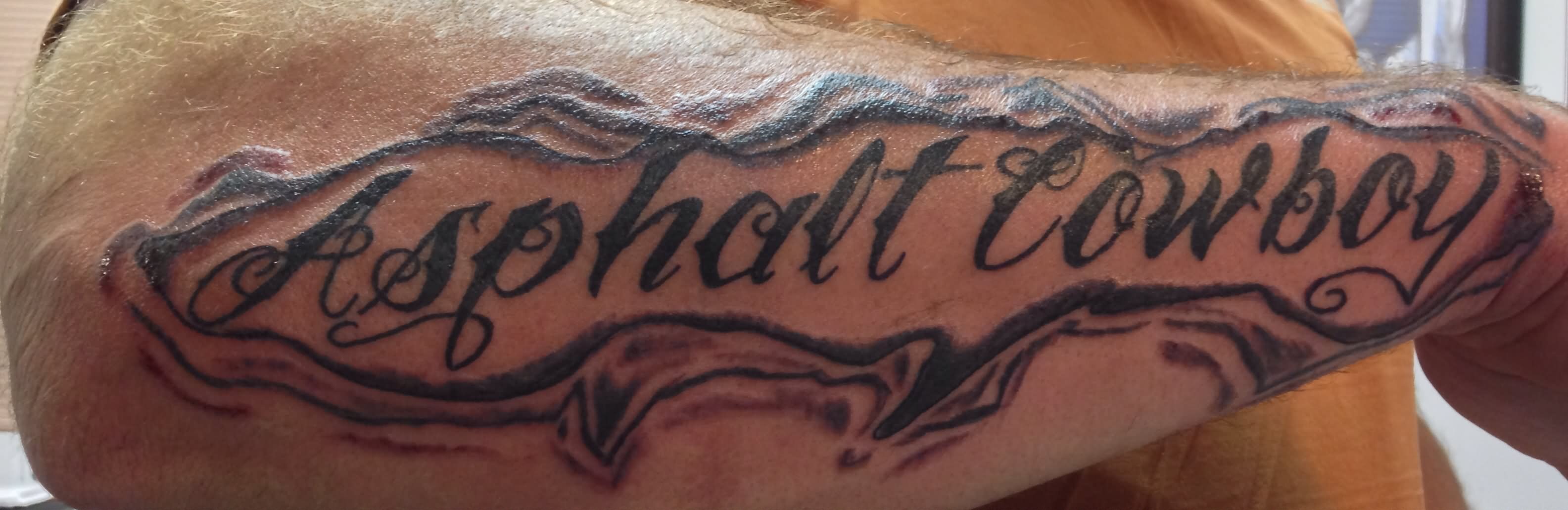 Asphalt Cowboy Lettering Tattoo On Forearm
