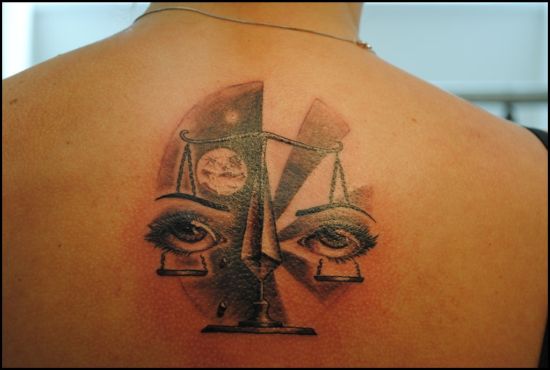 Grey Ink Eyes And Libra Tattoo On Man Upper Back