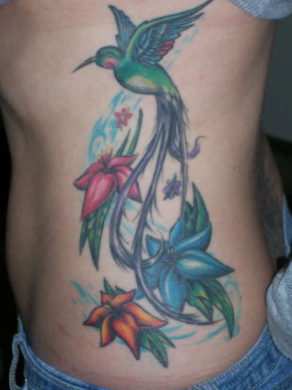 Colorful Flying Hummingbird With Flowers Tattoo On Side Rib