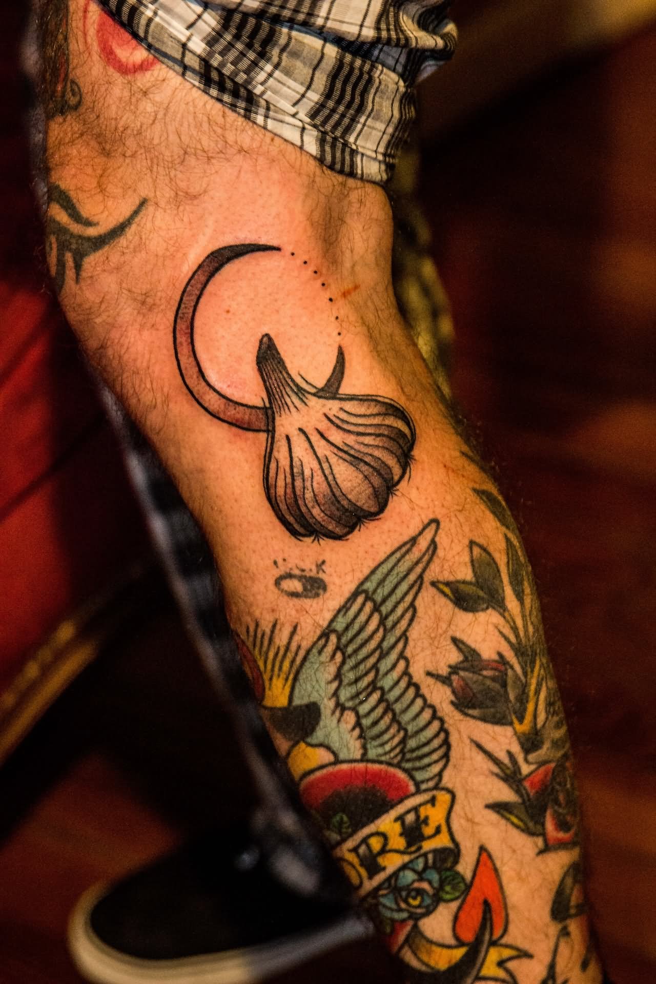 Black Ink Garlic With Half Moon Tattoo On Leg