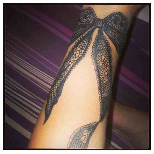 Black Ink Lace Ribbon Bow Tattoo Design For Forearm