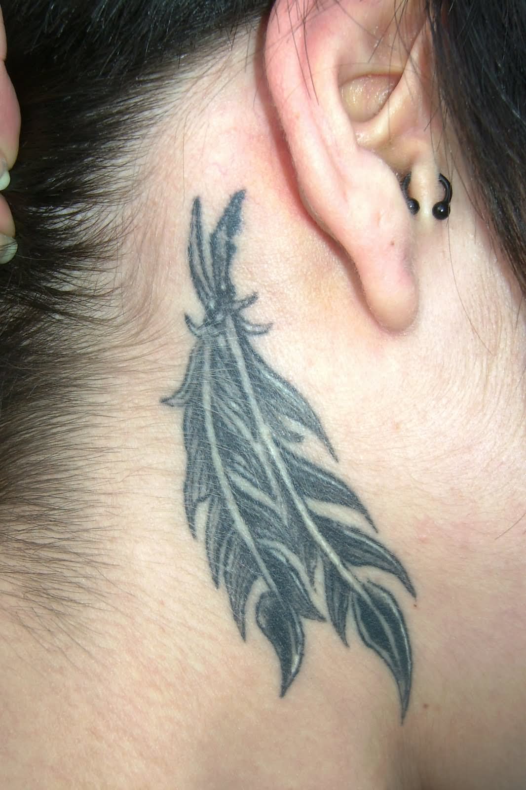 Black Ink Pigeon Feather Tattoo On Girl Behind The Ear