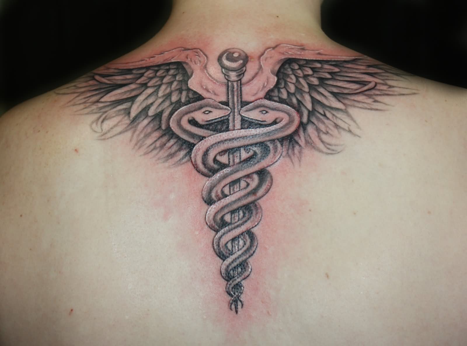 Black Ink Medical Symbol Tattoo On Upper Back
