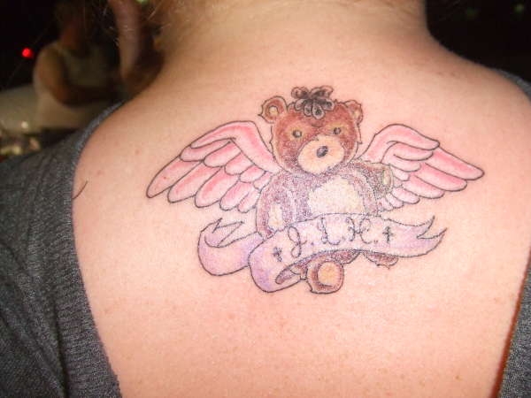 Memorial Teddy Bear With Wings And Banner Tattoo On Upper Back For Sister