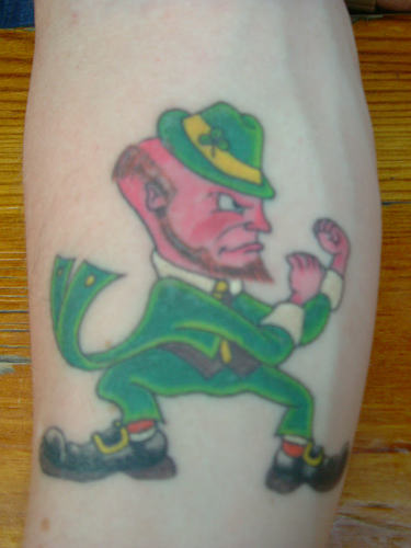 Pink Face And Green Dress Leprechaun Tattoo On Leg