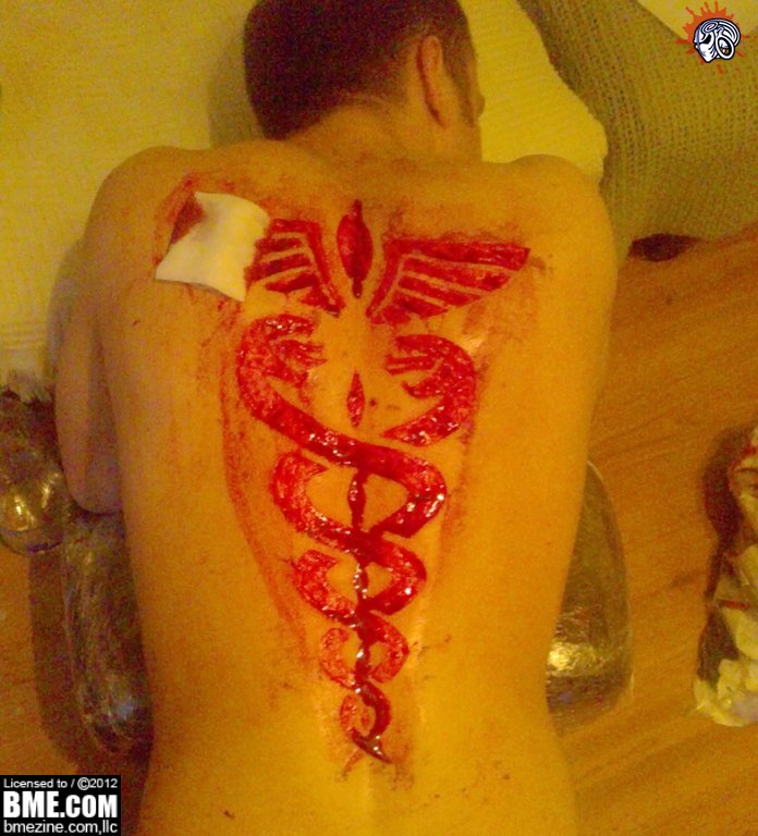 Red Medical Symbol Tattoo On Man Full Back