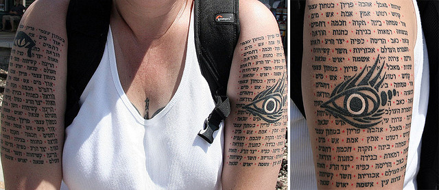 Black Eye With Hebrew Lettering Tattoo On Upper Arm