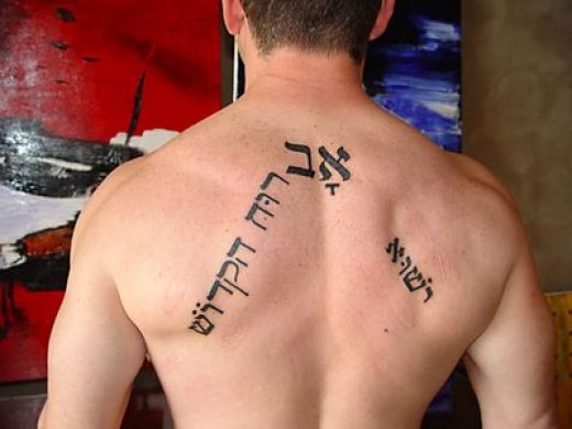Black Hebrew Phrases Tattoo On Man Upper Back