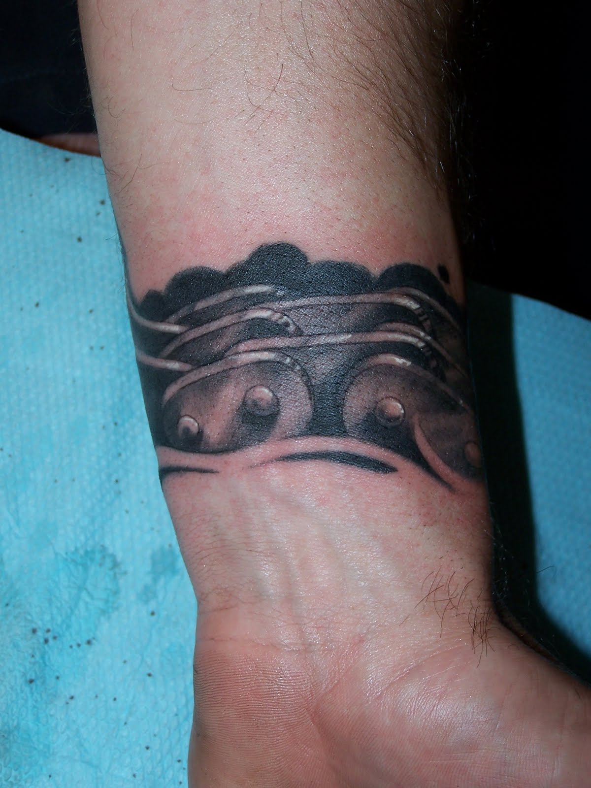 Grey Ink Motorcycle Chain Tattoo On Left Wrist