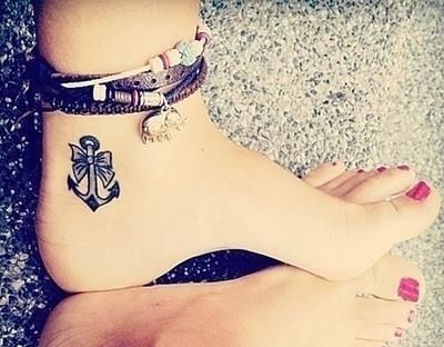 Black Ink Feminine Bow With Anchor Tattoo On Ankle