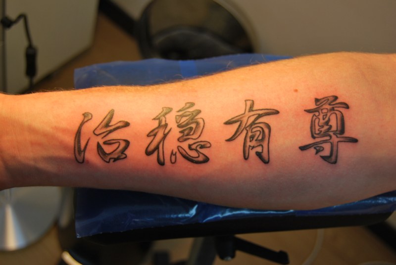 Black Ink Kanji Lettering Tattoo On Forearm