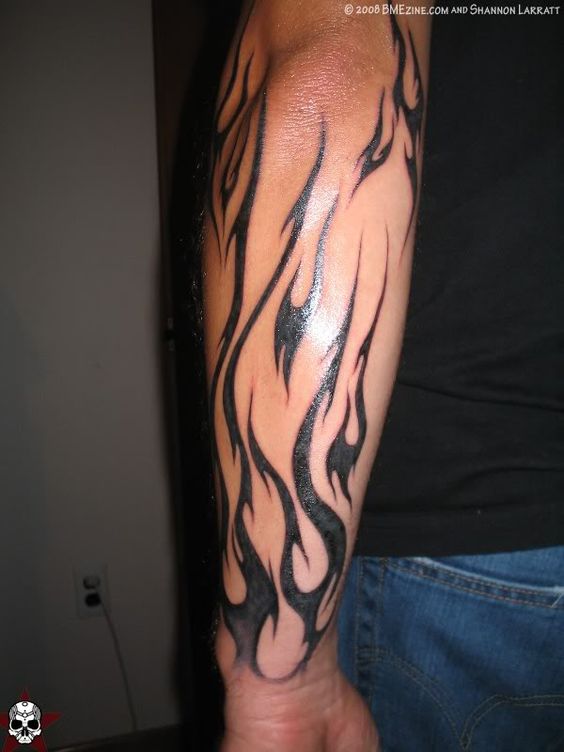Black Tribal Fire And Flame Tattoo On Man Left Forearm