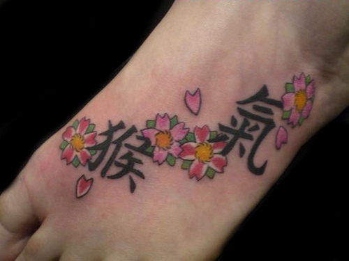 Kanji Lettering With Flowers Tattoo On Foot