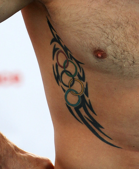 Tribal Design With Olympic Symbol Tattoo On Man Side Rib