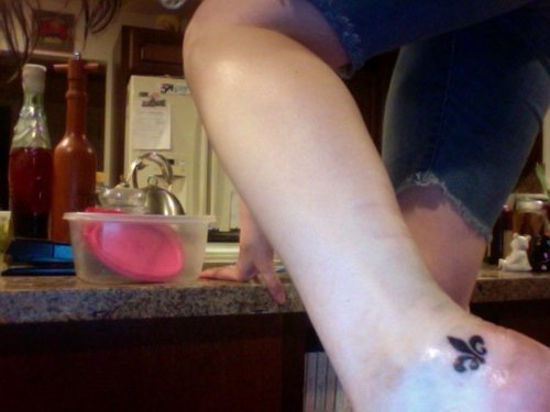 Black Ink Fleur De Lis Tattoo On Left Ankle