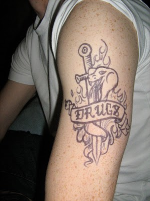Dagger With Drugs Banner Tattoo On Left Bicep