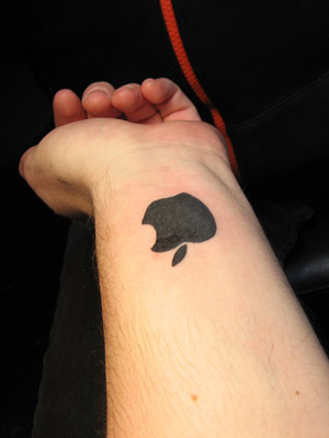 Black Apple Logo Geek Tattoo On Left Forearm