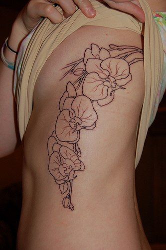 Girl Showing Her Black And White Orchid Tattoo On Side Rib