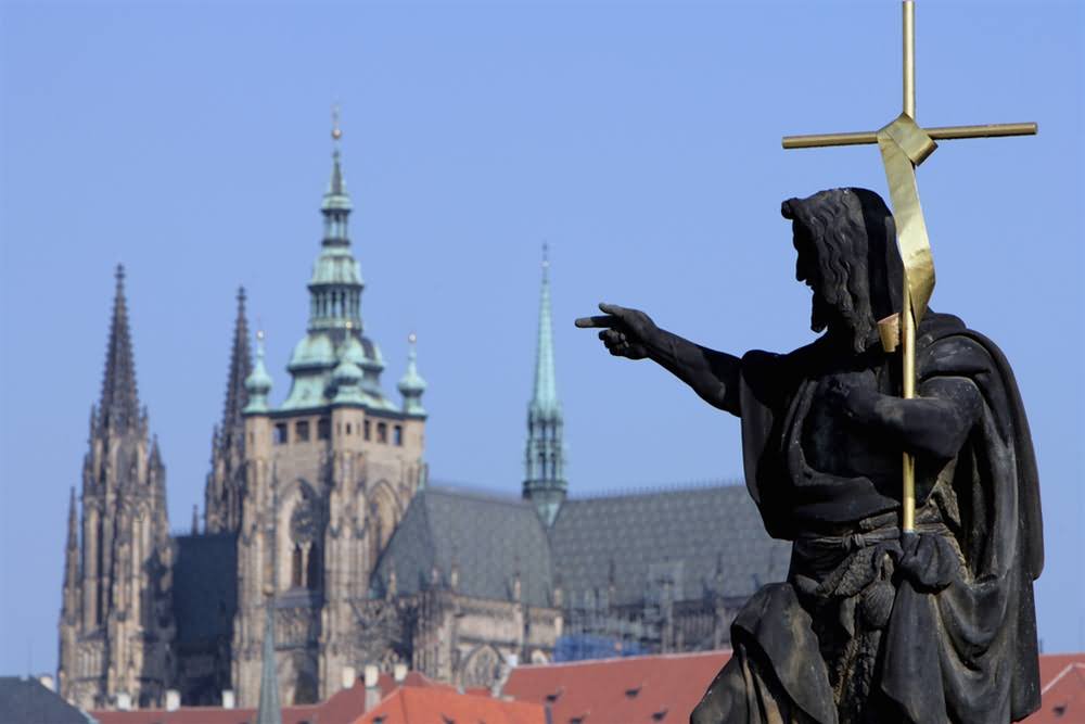 Statue At The Charles Bridge Pointing Towards The St. Vitus Cathedral