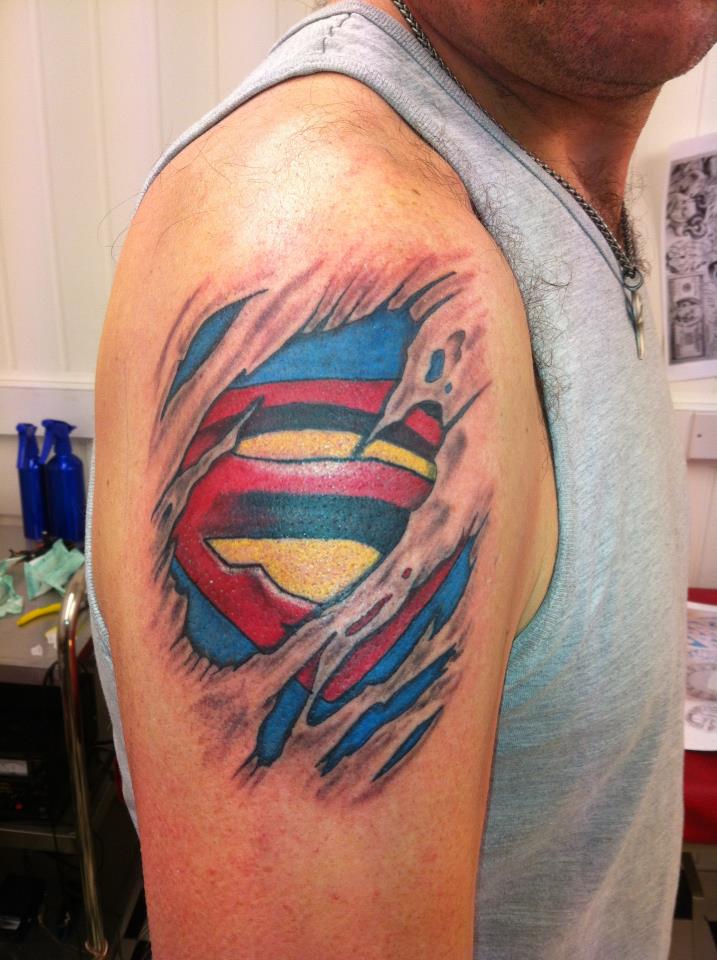 Torn Ripped Skin Superman Logo Tattoo On Man Right Shoulder.