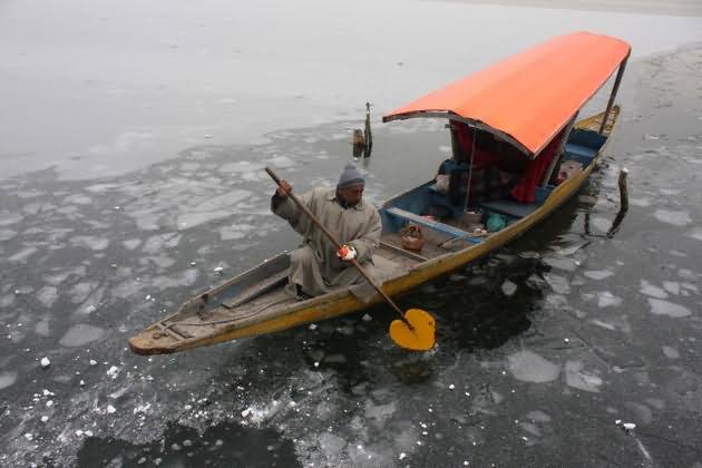 A Boatman Uses His Oar To Break Through Ice On Dal Lake In Winter Season