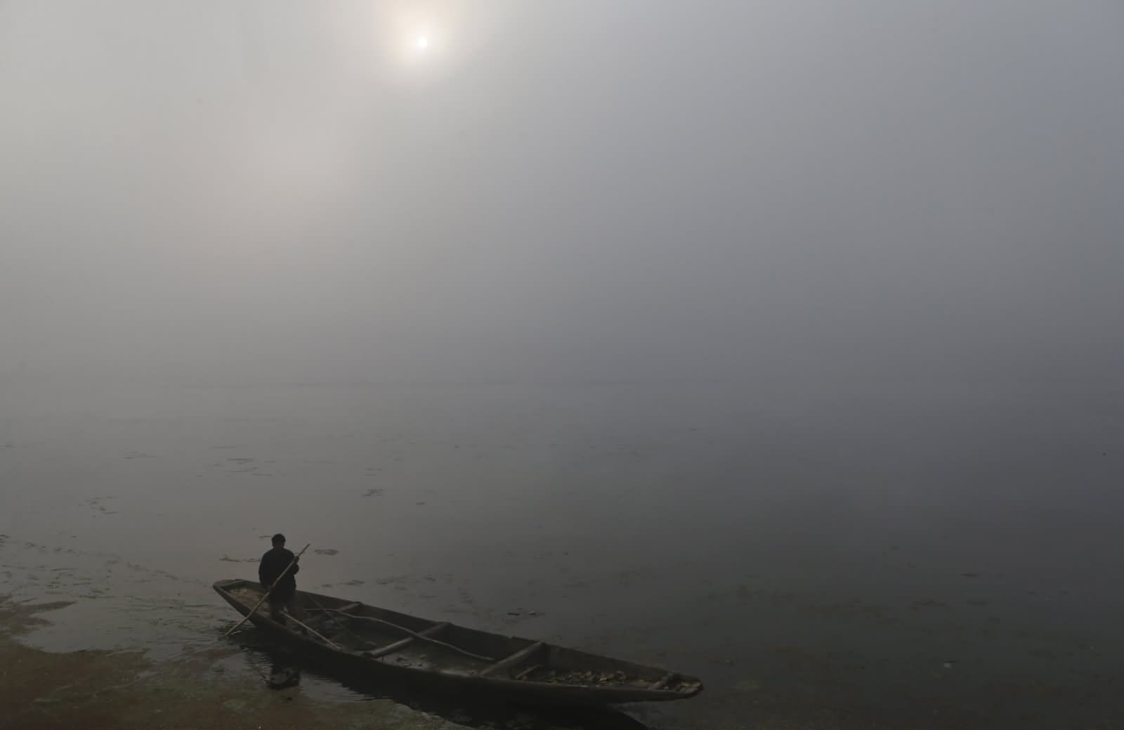 A Kashmiri Boatman Rows His Boat On The Dal Lake Surrounded By Dense Fog In Winter Season