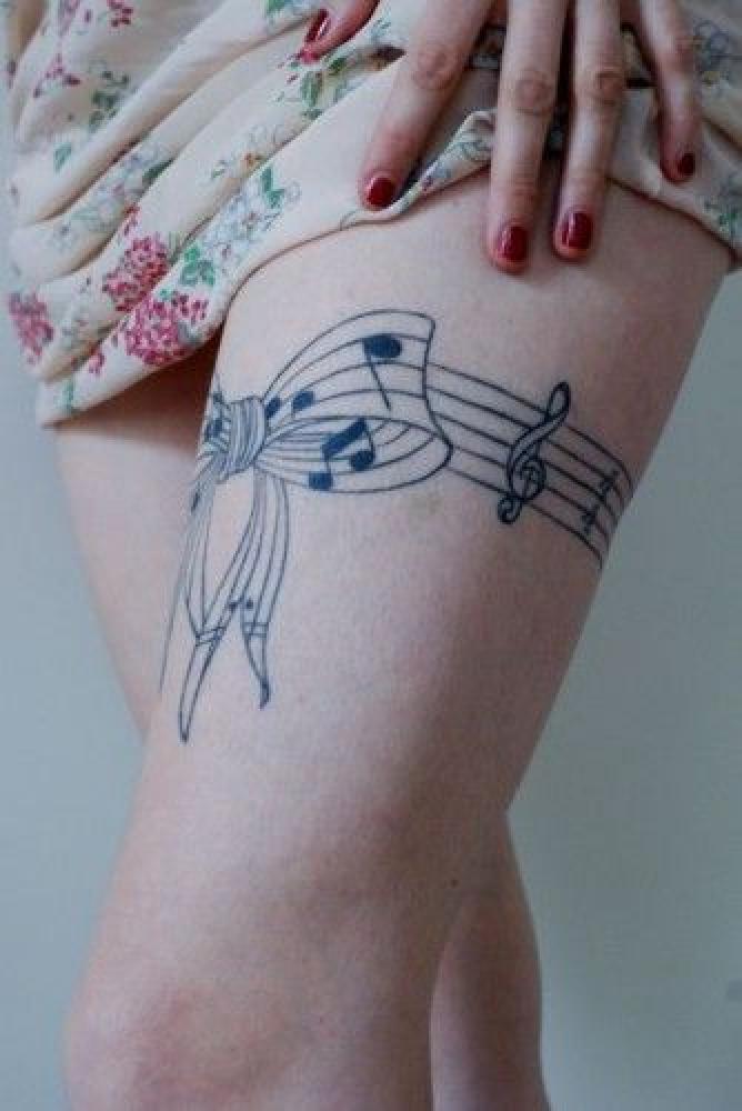 Music Notes In Bow Garter Tattoo On Left Thigh