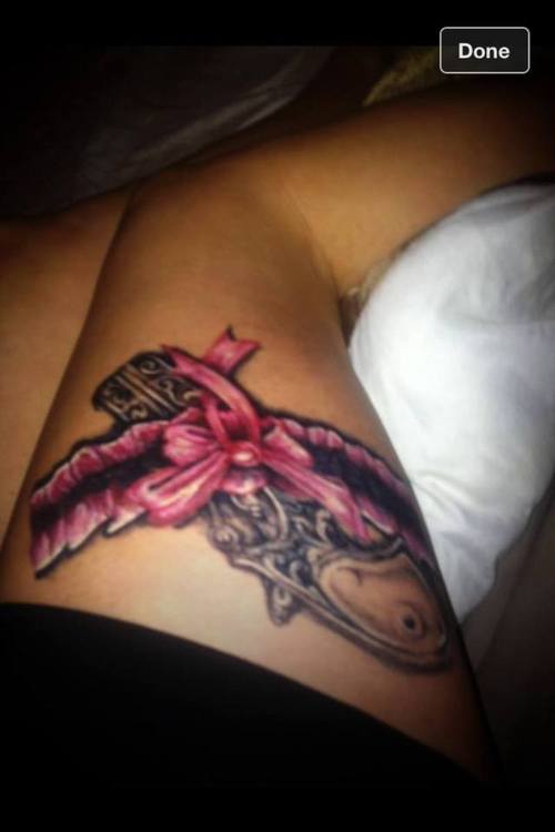 Pink Bow Gun And Garter Tattoo On Thigh