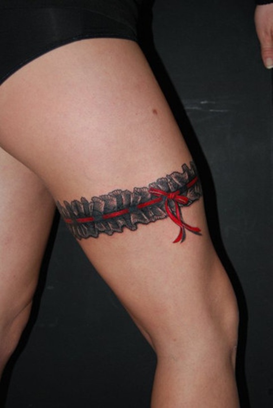 Red Ribbon And Black Garter Tattoo On Thigh