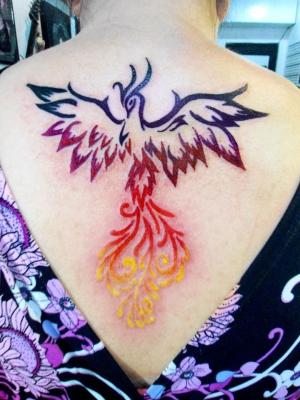 Colorful Rising Phoenix From The Ashes Tattoo On Girl Upper Back