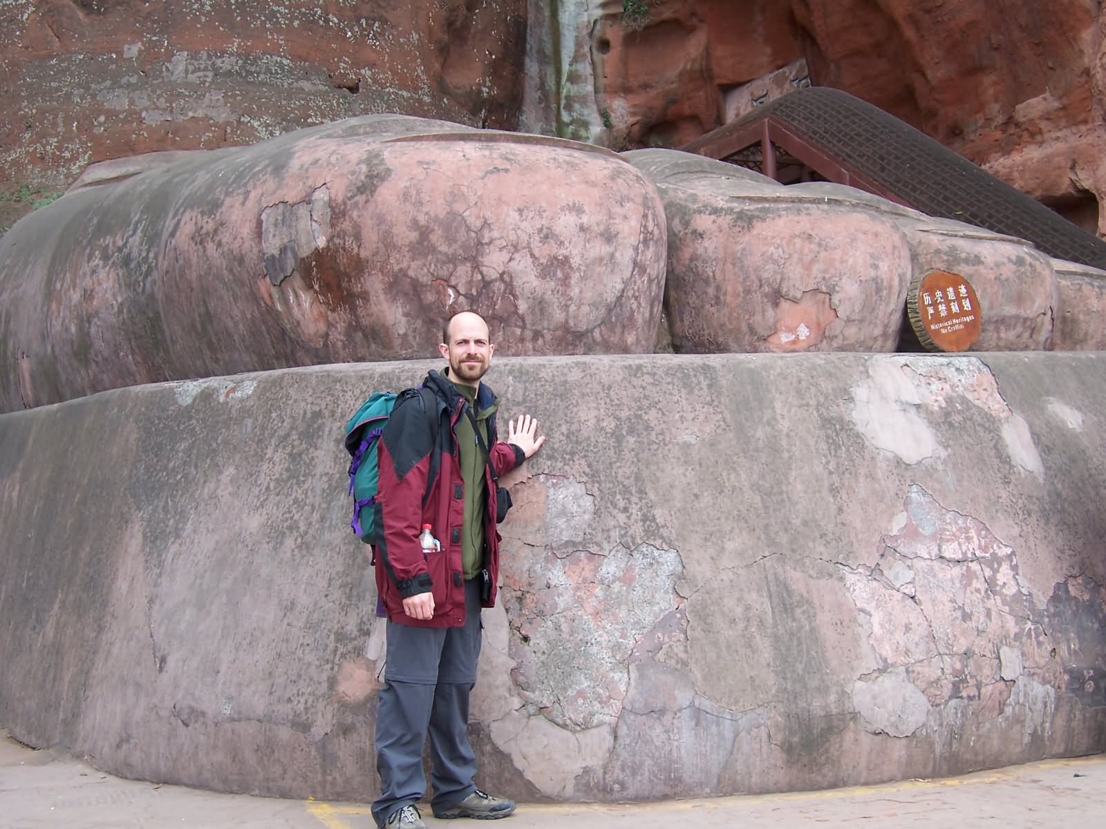 Man Standing With The Base Of The Leshan Giant Buddha Statue