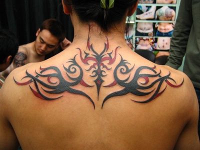 Red And Black Tribal Design Tattoo On Upper Back