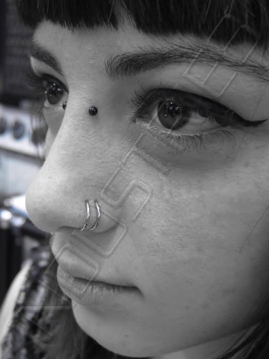 Silver Hoop Rings And Black Barbell Double Nose Piercing