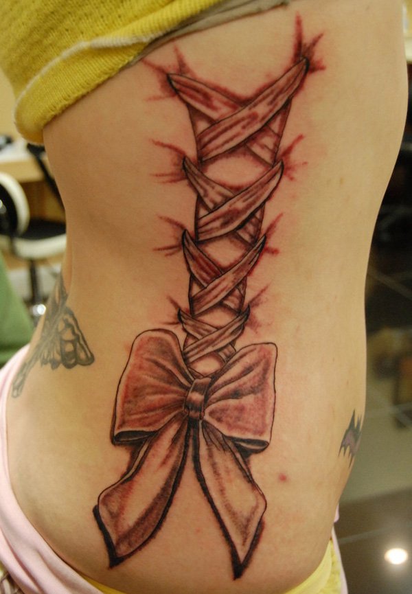 Amazing Corset Bow Tattoo On Girl Right Side Rib
