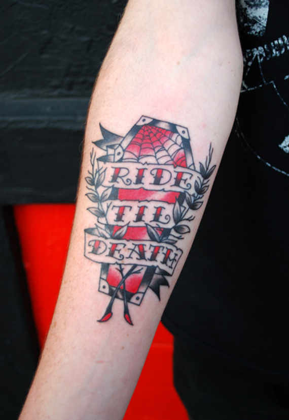Black And Red Coffin With Banner Tattoo On Forearm