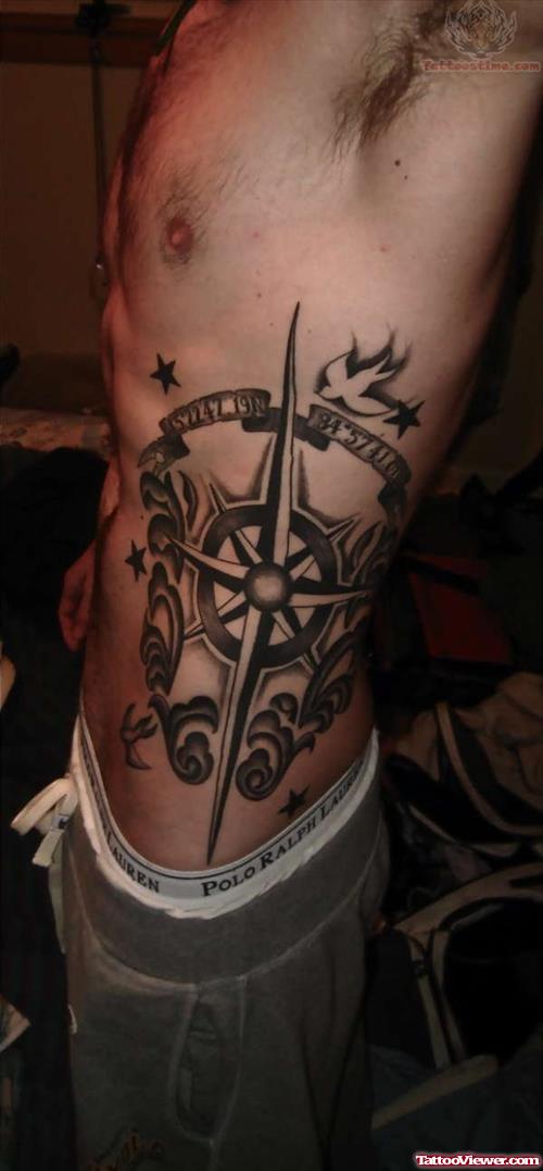 Black Ink Compass With Banner Tattoo On Man Left Side Rib
