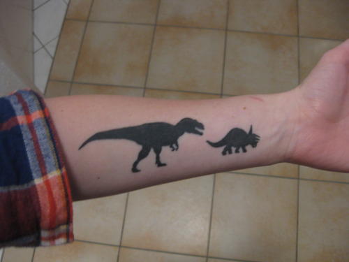 Black Ink Dinosaur Tattoo On Left Forearm