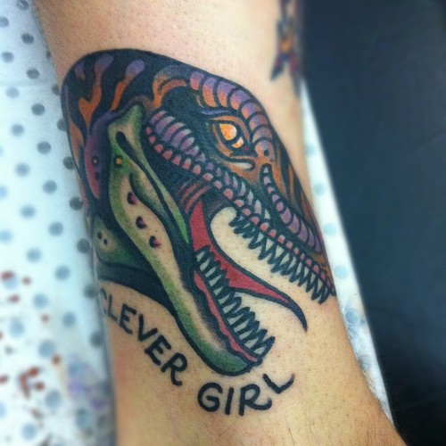 Clever Girl Dinosaur Head Tattoo On Leg by Chad Koeplinger