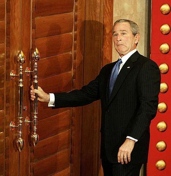 US President George W. Bush reacts as he tries to open a locked door after a news conference in Beijing