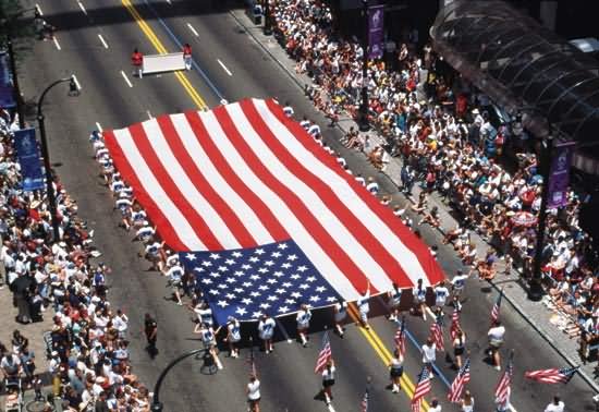 People Carry A Huge United States Flag In An Independence Day Parade